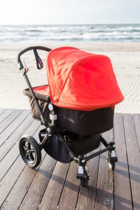 Red and black baby stroller on the sea background.